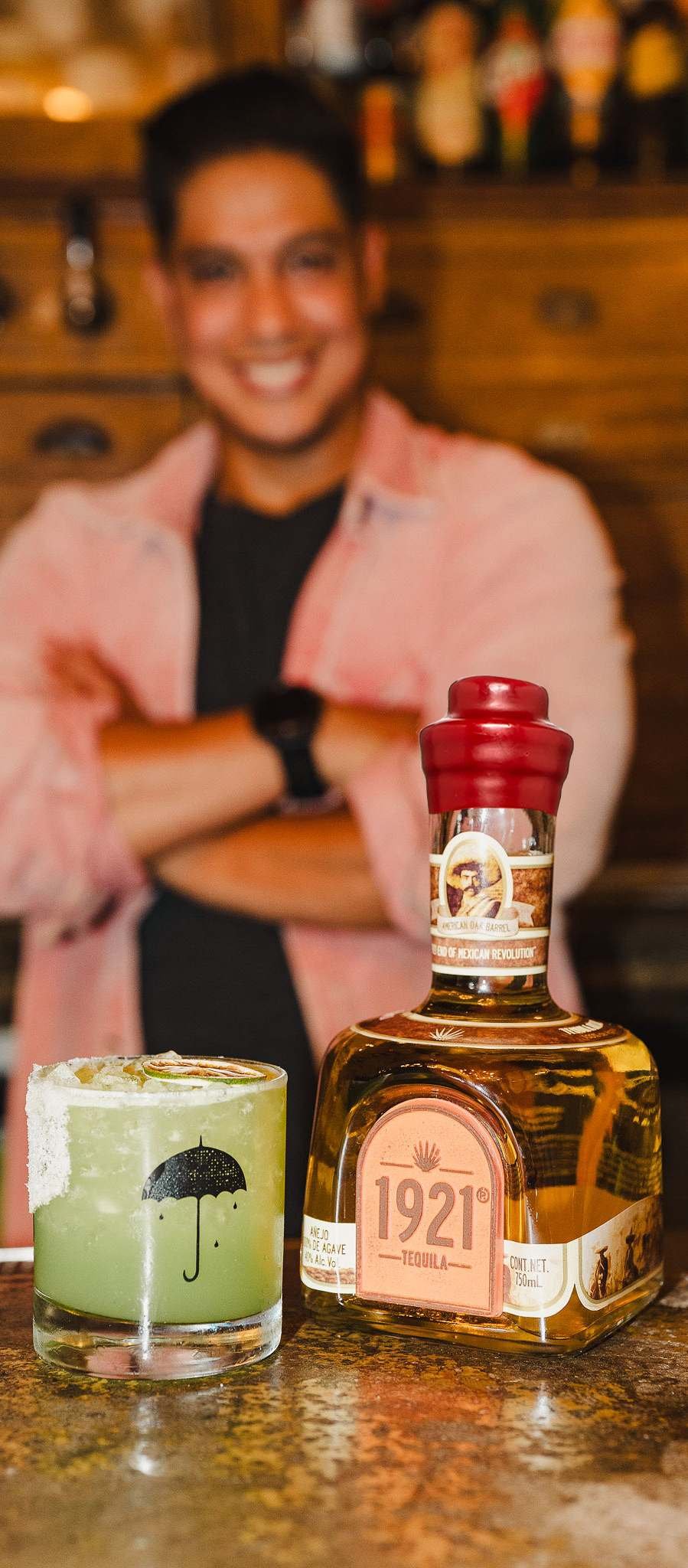 Hombre brindando con 1921 Tequila Añejo en la barra