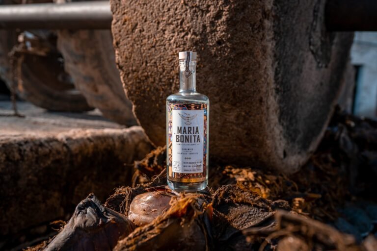 A bottle of Maria Bonita Mezcal Artesanal beside the stone tahona wheel used to crush cooked agave